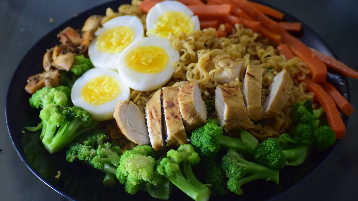 Assiette de nouilles avec poulet, brocoli, carottes et œufs durs, un repas riche en protéines