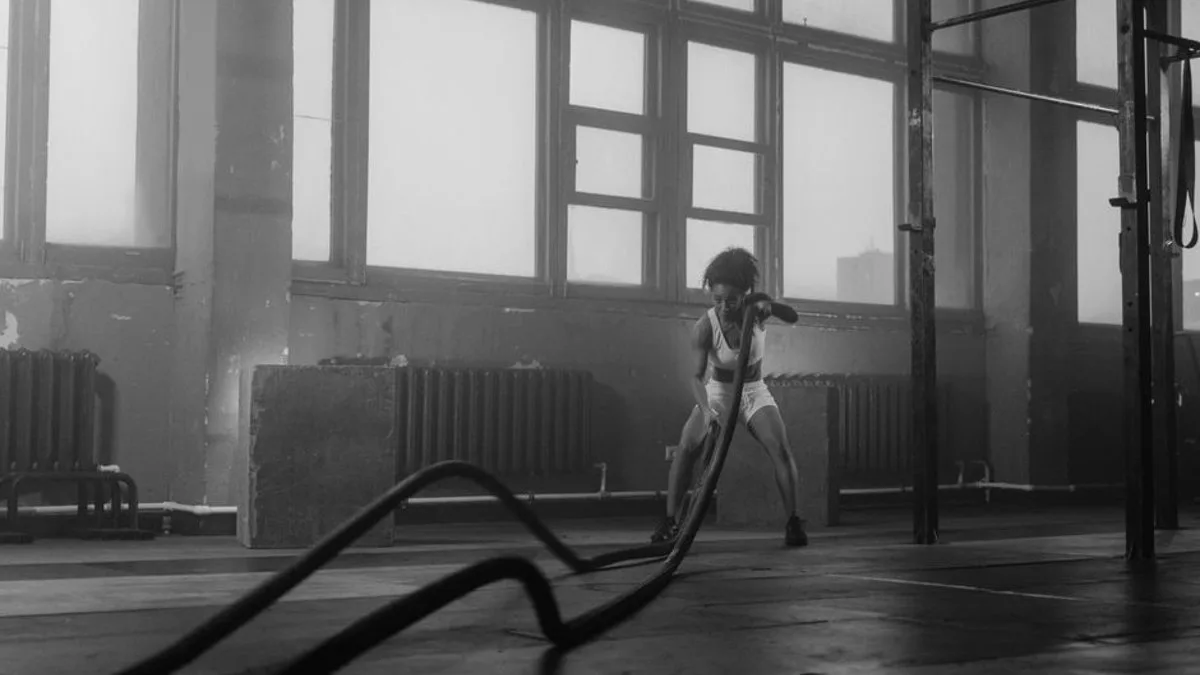Une femme en tenue de sport enchaîne des burpees dans une salle claire, essoufflée et concentrée