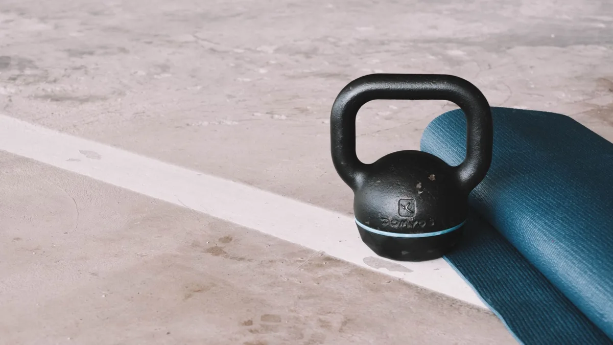 Kettlebell noire posée sur un tapis de sol bleu