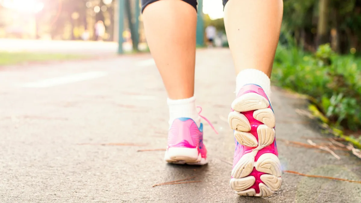 Pieds d'une personne en baskets roses qui marche sur un chemin