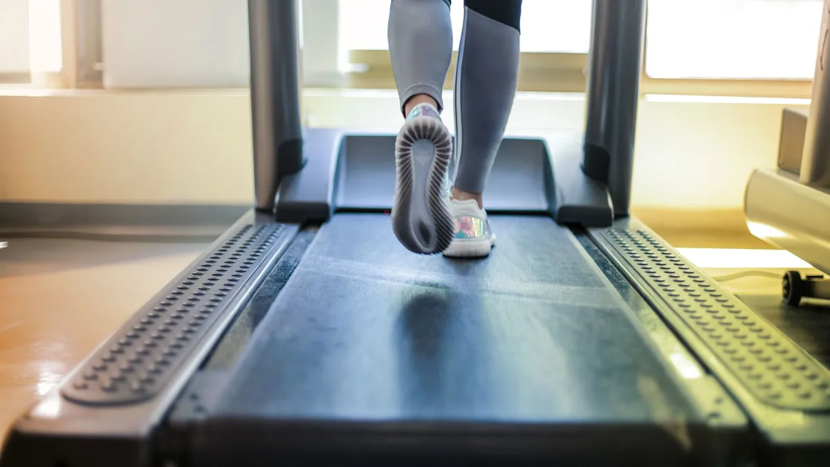 Pieds d'une personne qui court sur un tapis de course, vus de derrière